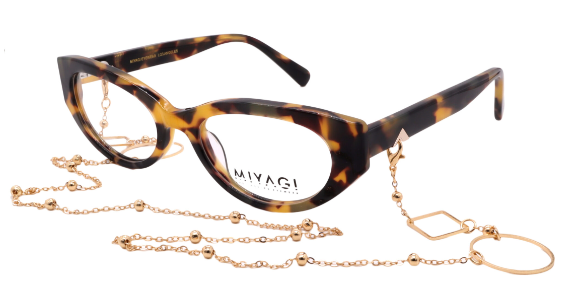 Tortoiseshell havana cat-eye optical frames with gold chain accessory, irregular shape.